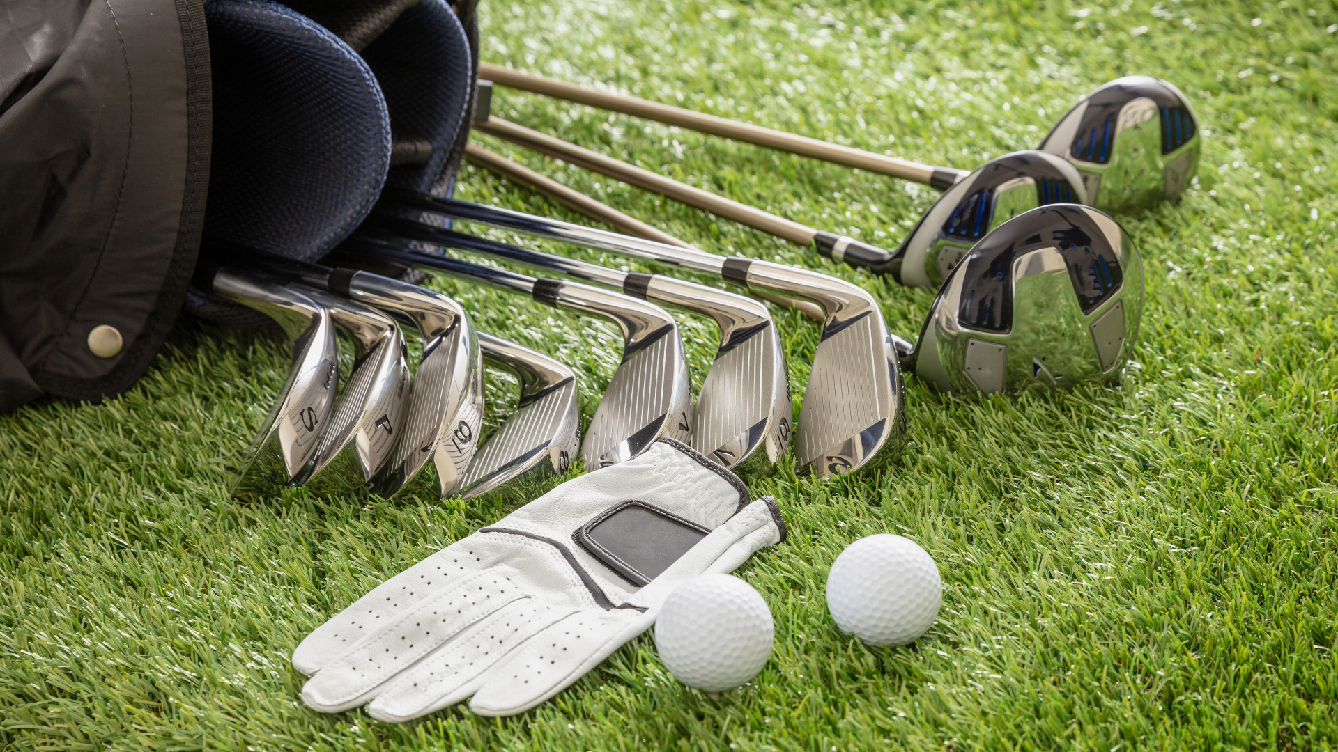 Golf bag laying on its side with golf clubs, a glove and two golf balls