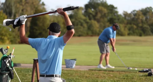 Golfer on a golf course stretching overhead with his golf club