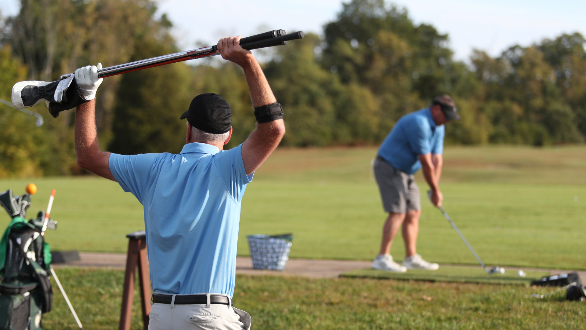 Golfer on a golf course stretching overhead with his golf club